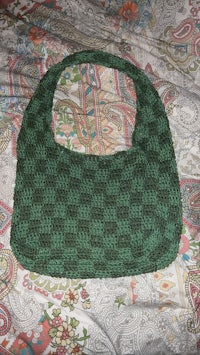 a green and black crocheted purse on a bed
