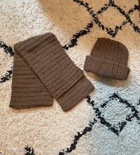 two brown crocheted hats and scarves on a rug